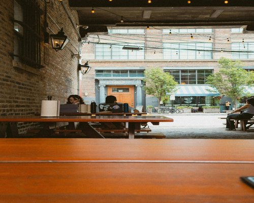 A modern shared workspace environment with people typing peacefully at wooden tables